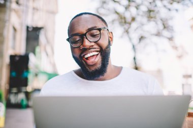 Zafer Yarışması zevk tasasız koyu tenli erkek video online dizüstü bilgisayar üzerinde boş zaman, online sosyal medya, başarı ile komik Afro-Amerikan blogger memnun izlerken de gülüyor
