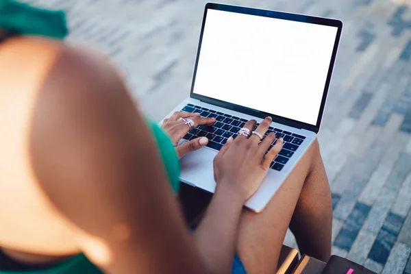 情報コンテンツを宣伝するための空白のコピースペース画面を持つラップトップコンピュータ上の女性の手のキーボードに選択的に焦点を当てます 膝の上にネットブックで屋外に座っている女性のトリミングされたリアビュー — ストック写真