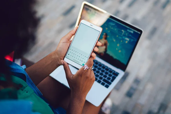 ディスプレイ上のデジタルキーボードと手白い携帯電話を保持している女性の背面クローズアップビュー 公共の無線を使用して技術で屋外に座っている間 スマートフォンでテキストメッセージを読む女性 — ストック写真