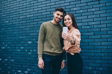 Birlikte duran akıllı telefon kamera selfie için poz rahat giyinmiş aşık neşeli çift, genç gülümseyen genç hipster kız ve adam modern cep telefonu uygulaması kullanarak ortak resim yapma