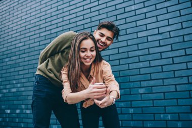 Neşeli erkek ve kadın hipsters akıllı telefon kamera birlikte serbest zaman harcama komik fotoğraf için poz, olumlu hipster çift eğlence cep telefonu uygulamasını kullanarak birlikte zaman zevk