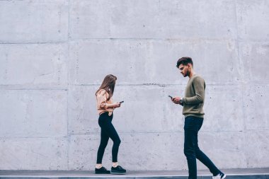 Erkek ve kadın hipsters onların akıllı telefonlar bakarak açık havada yürüyüş gerçek hayat görmezden, kız ve adam sohbet ve gadget'lar bağımlısı ağ için cep telefonu kullanarak konsantre yürüyüş
