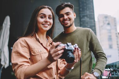 Şehirde vintage kamera kullanarak hobi serbest zaman harcama neşeli erkek ve kadın arkadaşlar Portresi, hipster çift kamera ve gülümseme bakarak görüntü çekmek için ekipman ile birlikte dinlenme