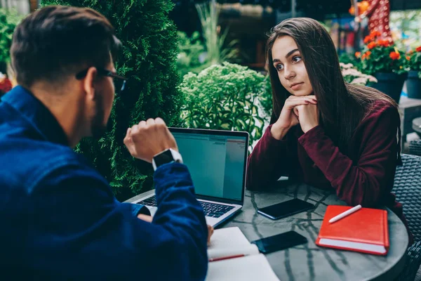 Serious Young Brunette Woman Listening Male Colleague Speaking Using Laptop — Stock Photo, Image