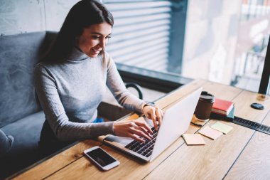 Kafeteryada sabah kahvesi sırasında bilgisayarda online komedi gösterisi izleyen neşeli gülümseyen hipster kız, mutlu kadın yazılım geliştiricidizüstü bilgisayar üzerinden çalışan ve mola sırasında komik videolar seyir