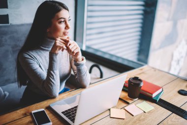 Wifi bağlı dizüstü bilgisayar üzerinden tabii dil online kırmak pencerede pencereye bakarak Dreaming hipster kız, pensive freelancer netbook ile ahşap masada oturan çatı iç kafede zaman zevk