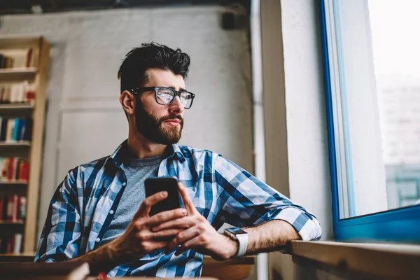 Tankefull Hipsterstudent Briller Som Ser Vinduet Mens Hun Oppdaterer Profil – stockfoto