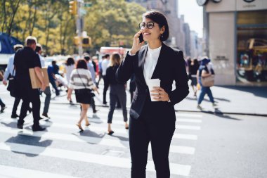 Kahve molası sırasında telefonda konuşan pozitif şirket yöneticisi dışarıda paket bardak tutarak, resmi giyim ve gözlük iş kadını iş arkadaşı ile mobil konuşma dinlenme zevk
