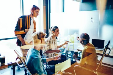 Yeni projede işbirliği yapan başarılı genç insanlar, modern ofis duvarının arkasında beyin fırtınası yapıyorlar. Kurslar sırasında eskiz çizmeyi tartışan başarılı hippi öğrenciler.