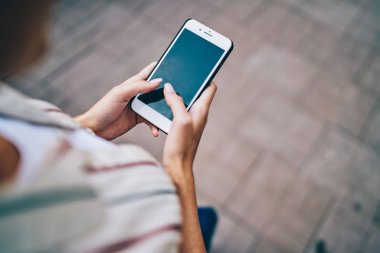 Sokakta yürüyen 4G internet bağlantısını kullanarak modern akıllı telefon cihazının ekranında yazı yazan kadınların üst kesitli görüntüsü. Cep telefonuyla sosyal ağlarda sohbet eden kadının parmakları
