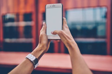 İnternet içeriğiniz için boş ekranlı modern akıllı telefonu tutan ve fotoğraf çekmeye odaklanan kadın elleri görüntüsü. Web siteniz için kopyalama alanı olan dijital cep telefonu