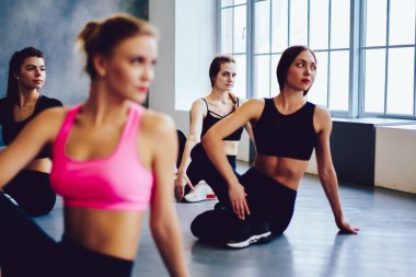 Eşofmanlı güçlü vücutlu başarılı zayıf kadınlar pilates egzersizlerinden önce esneme hareketleri yapıyorlar, bir grup neşeli kız stüdyo içinde eğleniyor, sağlıklı bir yaşam tarzı ve eğitim konsepti.