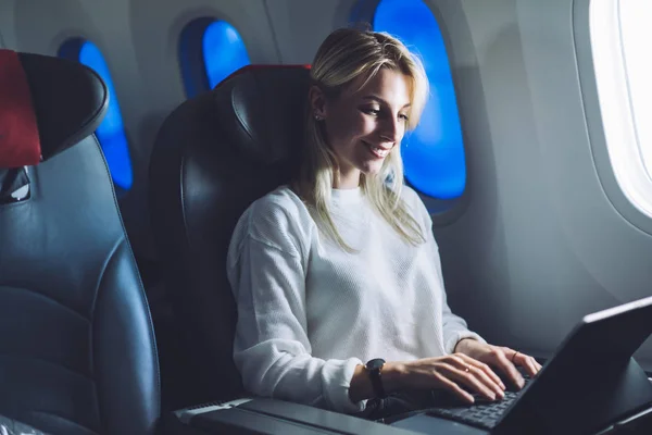 Smiling Female Aircraft Passenger Keyboarding Email Tablet Computer While Flying — Foto de Stock