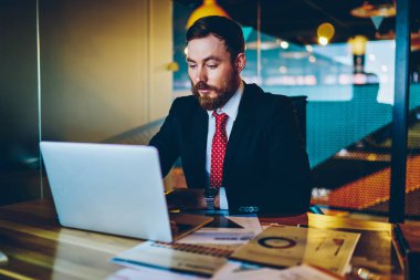 Resmi giyinmiş dalgın sakallı girişimci masaüstünde otururken modern dizüstü bilgisayarda iş webinar 'ı izliyor. Dijital netbook' ta çalışan konsantre erkek girişimci, e-posta yazıyor.