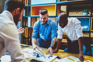 İş ortaklarının ortak ortak ortak bir proje üzerinde beyin fırtınası yapma süreci. Gömleklerle çok kültürlü girişimciler ofiste yaptıkları toplantıda grafik çizimleri ve kooperatif planı tartıştılar.