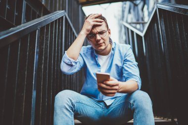 Endişeli genç adam elinde telefon tutuyor ve dışarıda merdivenlerde oturmakta başarısız olduğunu bildiren mektuplar okuyor. Hüsrana uğramış hipster adam mobil takvim uygulamasındaki olayı unutmuş. Sorunlar ve kriz
