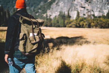 Yürüyüş turu sırasında dağda gezinen, manzaranın tadını çıkaran, turistik sırt çantalı, nefes kesici doğal manzaraya ulaşan erkek gezgin.