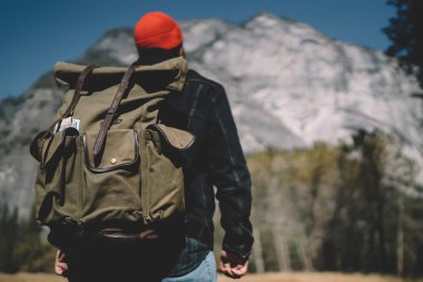 Sırt çantalı hippi adam dağlarda vahşi toprakları keşfediyor. Varış noktasına doğru yürüyor, erkek yürüyüşçünün dikiz aynasından milli parkın manzarasına bakıyor ve zirveye ulaşmanın yollarını keşfediyor.