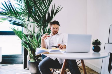 Sosyal ağlarda dizüstü bilgisayar okuyarak uzaktan çalışan kafası karışık erkek serbest çalışan ciddi bir beyaz adam, online iş için modern netbook kullanıyor ve dosyaları indiriyor.