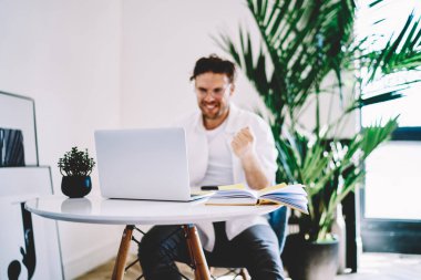 İnternet sitelerini taramak için ev internetine bağlı modern dizüstü bilgisayara seçici bir odak, web mağazasında yaklaşan satışlarla ilgili iyi haberlerle gelen mutlu adam