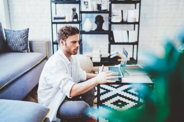 Gündelik giyinmiş genç bir adam, yerde oturmuş, akıllı telefon cihazına mesaj yazarken meslektaşlarıyla çevrimiçi konferans için beklerken, 4G kablosuz internet bağlantısı olan serbest çalışan bir erkek.