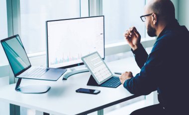 Bilgisayar ve dizüstü bilgisayarlar üzerinde çalışan genç bir çalışan. Ekranda mali bilgi grafikleri var ve ofis masasında oturuyor. Başarılı bir muhasebe işadamı gelir ve araştırma yapıyor. Milenyum çalışması.