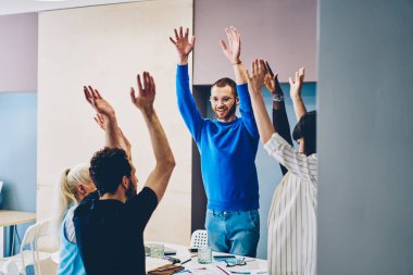Verimli işbirliğinden memnun duygusal erkek ve kadın öğrenciler birbirlerine beşlik çakıyor, çok ırklı çalışanlardan oluşan bir ekip başarılı projeyi ofis içinde kutluyor.