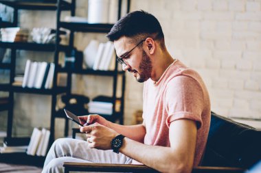 Dairenin boş zamanlarında dijital tablette ücretsiz ev interneti kullanan ve serbest metin yazarları için bilgi içeren içerik web sitesinde haberlerini okuyan sıradan görünümlü yakışıklı hippi.