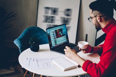 Web sitesinde webinar okuyan genç adam modern dizüstü bilgisayardaki internet bağlantısını kullanıyor, erkek öğrenci ev içi eğitim sırasında internet sayfaları üzerinden bilgi topluyor