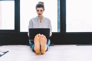 Ayakları kamerada yerde oturan ve dizüstü bilgisayardaki kablosuz bağlantıyı kullanarak internet sitelerinde bilgi arayan düşünceli genç bir kadın. Evde netbook 'ta çalışan konsantre olmuş serbest çalışan biri.