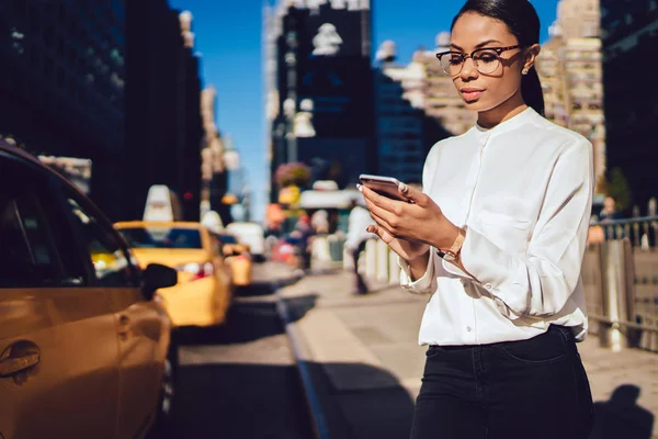 Confident woman entrepreneur received text message on cellular about roaming connection in New York during business trip to Manhattan, dark skinned female checking notification on smartphone device