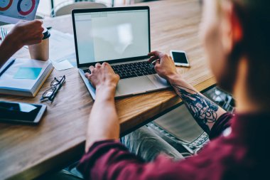 İnternetin taranması için 4G kablosuz ağ kullanarak yeni bir iletişim sitesi oluşturmak için yazılım kodları yazan erkeğin arka görüntüsü, netbook üzerinde uzaktan çalışan dövmeli eller