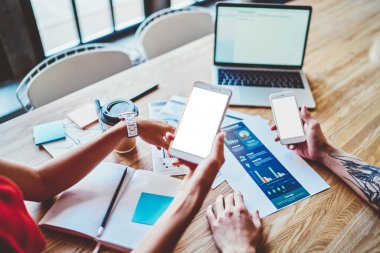 İnternet reklamınız veya web siteniz için boş ekran alanına sahip modern akıllı telefon aygıtlarını tutan ve medya dosyaları aracılığıyla bilgi paylaşmak için bluetooth bağlantısı kullanan ellerin kesilen üst görünümü