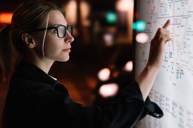 Toplu taşıma metro haritalı dijital monitör. Gelişmiş yenilikçi teknolojiyle büyük ekranda duran kadın. Yüzey seçeneğini seçerken parmağa duyarlı ekranla dokunan genç kadın
