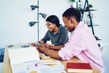 Neşeli Afro-Amerikan çifti internet sayfasında satışla ilgili bilet rezervasyonu yaptığı için mutlu. Laptop bilgisayar kullanıyor, gülümseyen koyu tenli hippi adam multimedyayı cep telefonundan Netboo 'ya paylaşıyor.
