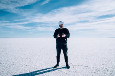 Erkek, boş, ferah bir fotokopi alanı manzarasında oyun alanıyla dışarıda dururken sanal gerçeklik oynarken merak duygusunu ifade ediyor. Kontrol kumandası kullanarak VR oyununu keşfeden tam uzunluktaki adam