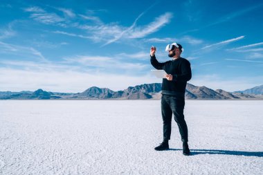 İnsanoğlunun tam uzunluğu sanal gerçeklik boyutu yaratmak için kulaklık taktığı dijital kalem simülasyonu alanına dokunuyor. Erkek artırılmış sanal gerçeklik ortamını kontrol etmek için tablet bilgisayar kullanıyor.