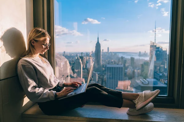 風光明媚なマンハッタンのダウンタウンのパノラマの景色と同僚のオフィスでリモートで作業ノートパソコンのコンピュータ上の女性のフリーランサーのキーボード情報を集中 学生交流とニューヨークへの旅行 — ストック写真