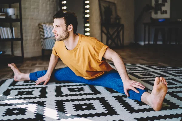 Konzentrierter Junger Mann Sitzt Bindfaden Und Macht Dehnübungen Während Des — Stockfoto