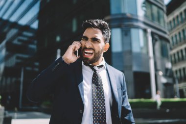 Öfkeli yetişkin erkek yönetmen, uluslararası arama sırasında kötü haber aldığı için kızgın. Akıllı telefon uygulaması ile konuşurken çalışana bağıran, suratında çılgın bir ifade olan adam.