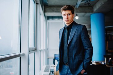 Resmi olarak şirketin kendine güvenen sahibinin yarı boy portresi ofiste duruyor. Yakışıklı, beyaz, şık takım elbiseli bir erkek girişimci kameraya özenle bakıyor.