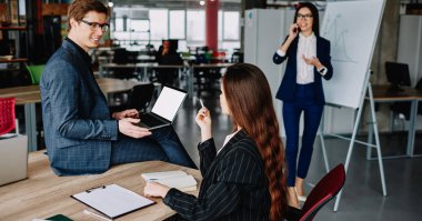 İş kadını dizüstü bilgisayarı erkek meslektaşlarının elinde işaret ediyor. Çalışma sırasında sohbet ediyorlar. Resmi çalışan profesyonel ekip verimli bir işten memnun.