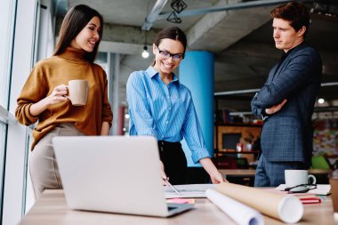 Mutlu kadın tasarımcı, ofisteki iş arkadaşlarıyla işbirliği yaparak tamamlanmış çizimden memnun, verimli bir iş için heyecanlı deneyimli mimarlardan oluşan başarılı bir ekip.