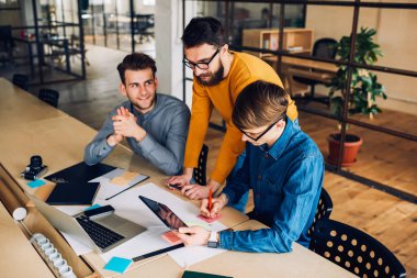 Geliştirme projesinde profesyonel öğretmenle birlikte çalışan yetenekli öğrenciler masaüstünde oturuyor ve arama bilgileri için modern tablet kullanıyorlar, çizimdeki genç mimarların işbirliği