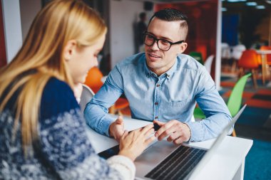 Bilgisayarla masadaki toplantı sırasında akıllı telefondan komik tebligat alan pozitif hipster öğrencileri. Cep telefonu uygulaması hakkında birbirleriyle iletişim kuran başarılı meslektaşlar.