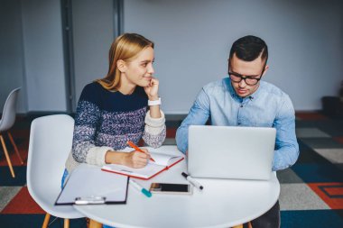 Ödev yazan ve gelecek sınavlara dizüstü bilgisayar ve internet bağlantısını kullanarak hazırlanan iki yetenekli öğrenci. Masaüstünde bilgisayarla oturan ortak proje üzerinde çalışan profesyonel tasarımcılar