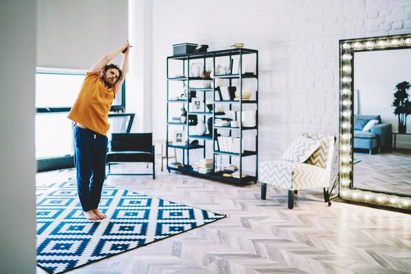 Erfahrener Junger Mann Der Auf Teppich Steht Und Bei Yoga — Stockfoto