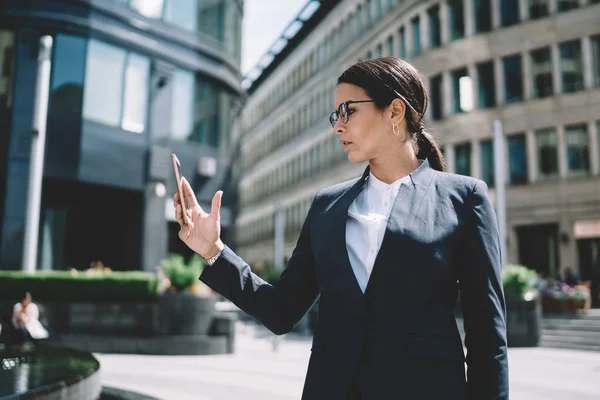 金融街で公衆無線Lanに接続されているスマートフォンのガジェットにファイルをダウンロードするためのアプリケーションをインストールする深刻な女性企業の取締役 ビジネスの人々と通信の概念 — ストック写真