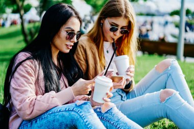 Kafkasyalı genç bayan arkadaşlar birbirleriyle konuşuyor ve açık havada cep telefonlarıyla multimedya paylaşıyorlar. Hippi kızlar kampüste boş zamanlarını akıllı telefonlar ve 4G internet kullanarak geçiriyorlar.