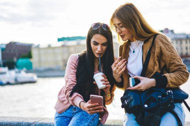 Genç bayan turistler, şehir turu sırasında internet haritasını ve güzergahını kontrol etmek için 4G bağlantısı kullanıyorlar, genç hippi kızlar kahve içiyor ve modern uygulamayı sokakta ayakta durmak için kullanıyorlar.